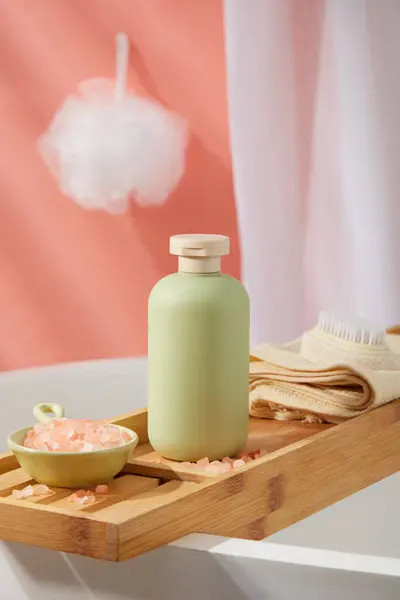 用浆糊色的瓶子放在浴缸盘上 盘上有粉红的希玛拉盐和一条用毛刷擦拭的毛巾 墙上挂着白色的浴巾 品牌模型的空白标签 — 图库照片