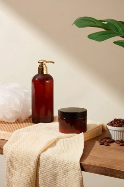 Etiketi olmayan bir pompa şişesi ve kavanoz, küçük kasede kahve çekirdekleri ve beyaz arka planda yeşil yapraklar. Vücut bakımı ürünlerinin reklamını yapmak için en az konsepte sahip bir sahne.