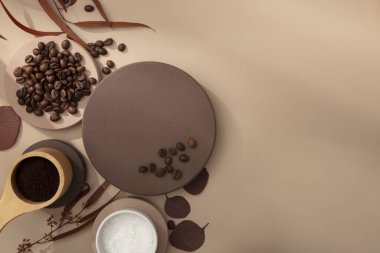 Üst manzara, yuvarlak podyumlarla süslenmiş düz kahve çekirdekleri ve kahverengi arka planda kuru dal yaprakları. Ürün sunumu için podyumda boş alan. Boşluğu kopyala