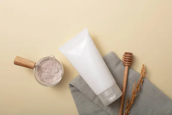 米糠粉储存在玻璃碗里 一管没有品牌的面部清洁剂 一块布和一个蜂蜜毛毛雨显示在苍白的背景上 天然化妆品模型 — 图库照片