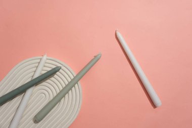 Beyaz ve gri mumlar pembe arka planda kubbeli bir podyumda sergilenir. Ürün gösterimi için boş alan. Reklamcılık ve daha fazlası için yaratıcı alan.