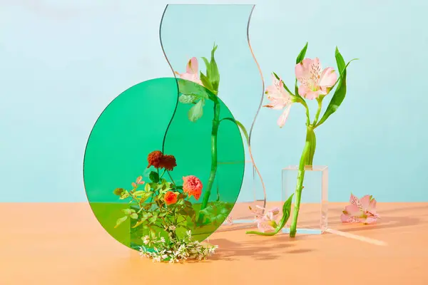 Green circular acrylic sheet is displayed with a mirror, the surrounding is decorated with fresh flowers on a pastel background. Art space for cosmetics advertising.