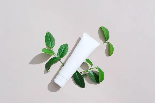 The antioxidant, anti-inflammatory and antibacterial properties in green tea are applicable in the treatment of acne and oily skin. Facial cleanser tube with green tea leaves on white background.