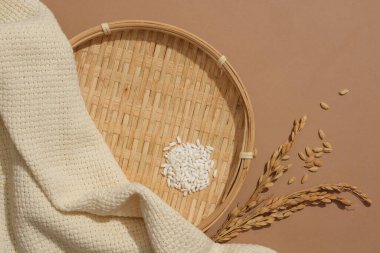 Düz pencere sepeti, beyaz pirinç, tam tahıllı pirinç ve kahverengi arka planda sergilenen bej kumaş. Yeni ürünlerin reklamını yapmak için ideal alan.