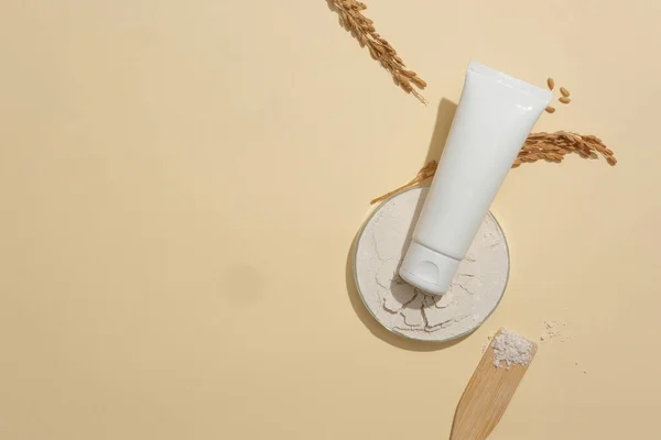 A labelless cosmetic tube stands out against a minimalist beige background. Building a vegan cosmetics brand with main ingredients from rice bran. Copy space.