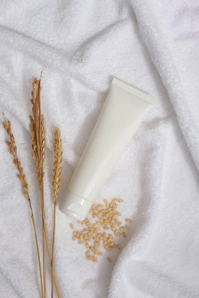 Buğday kulağı, buğday tohumu ve markasız tüple dekore edilmiş beyaz havlu. Boş etiketli doğal cilt bakımı kavramı