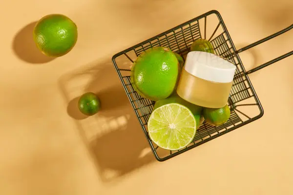 一个没有标签的化妆品罐子被放在一个装有新鲜柠檬和苦瓜的铁筐里 柠檬中的酸可以减少面部疤痕 纯素化妆品广告的饮料 — 图库照片