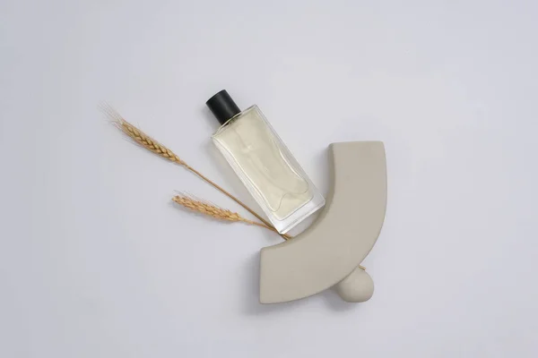 Bottles of cosmetic essential oil on white background with gray prop and wheat. Minimal scene for advertising perfume product. Top view, mockup bottle unlabeled for design