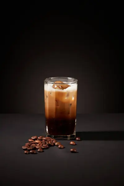 Close-up of a cup of coffee with coffee beans on a mysterious black background. Coffee contains B vitamins and anti-inflammatory agents that can prevent acne caused by dermatitis.