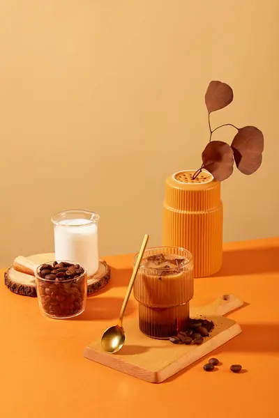 一杯牛奶咖啡和咖啡豆在木制切菜板上 周围都是橙黄色背景的道具 咖啡豆对健康有许多好处 — 图库照片