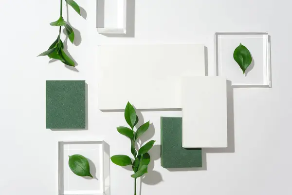 白い背景 3つのガラスプラットフォーム 4つの表彰台 緑の葉に対して 魅力的な構成を形成します 商用ビジュアルを魅了するための寛大な空きスペースでテキストを作成する — ストック写真
