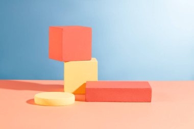 Mavi sırtlı, yuvarlak ve dikdörtgen podyumlarla düzenlenmiş iki küp kürsü yığını. Asgari tasarımda soyut kompozisyon