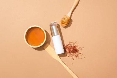 Etiketsiz şişe bir kase bal, safran ve kaşık balmumuyla süslenmiş. Cilt bakımı maketi. Kozmetik güzellik şişesi. Bal özüyle yüz maskesi.