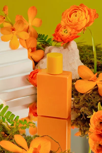 Zbliżenie Pomarańczowej Butelki Perfum Wyświetlanej Tle Żywych Kwiatów Zielonych Liści — Zdjęcie stockowe
