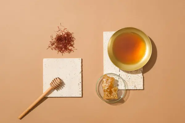 A handful of saffrons, honey dripping, golden bowl of honey and a glass petri dish of beeswax. Beige background. Honey helps relieve cough in children