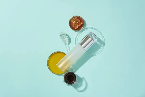 Luxury cosmetic bottle, honey in a petri dish, and a honey drizzle showcased against a blue background. Honey's natural properties balance skin bacteria, offering protection against infections.