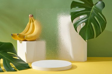 Modern geometrik şekilli podyum kompozisyonu, şeffaf akrilik çarşaf ve muz demeti. Muz özetinin ürün tanıtımı için podyumda boş alan