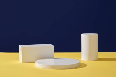 Renkli bir arkaplan üzerinde düzenlenmiş yuvarlak ve dikdörtgen beyaz platformların ön görünümü. Minimum sahne modeli kozmetik ürün sahne gösterisi