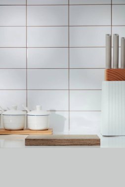 Mutfak içi beyaz fayans zeminiyle dekore edilmiş. Baharat kutusu, bıçak tepsisi ve sergi için boş ahşap bir podyum. Reklam ürünleri için mutfak arka planına sahip boş bir sahne.