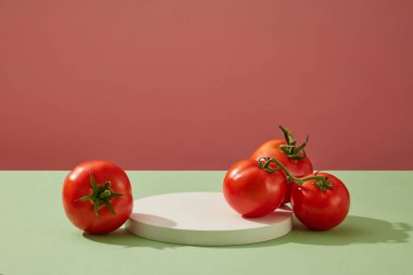 Ürün markası sunumu için minimalist tarzda soyut bir arka plan, taze domateslerle süslenmiş yuvarlak beyaz bir podyum. Ön görünüm, boşluğu kopyala
