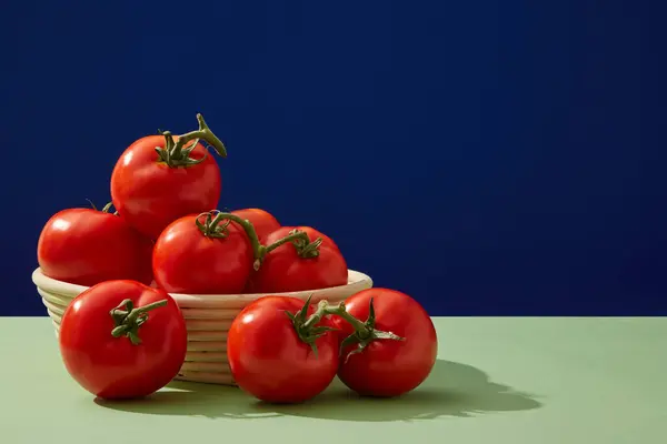 ダークブルーの背景に新鮮なトマトをたくさん含む丸いバスケットのフロントビュー トマトの成分を配合した化粧品のブランクスペース コピースペース — ストック写真