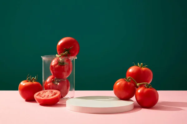 新鮮なトマトと濃い緑の背景にビーカーで飾られた丸い白い表彰台 パッケージ製品のデザインとディスプレイのためのスペース 化粧品の広告 ブランディング — ストック写真