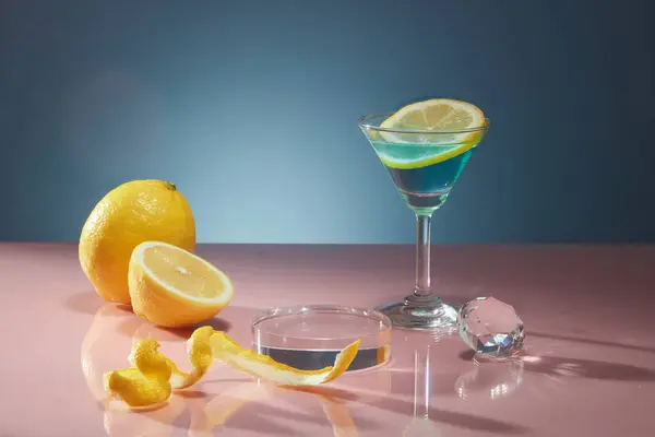 新鮮なレモンの皮とスライスは ガラスカップとクリスタルボールで濃い青色の背景に装飾されています レモン抽出物の表示プロダクトのための透明な表彰台の空のスペース 広告写真 — ストック写真
