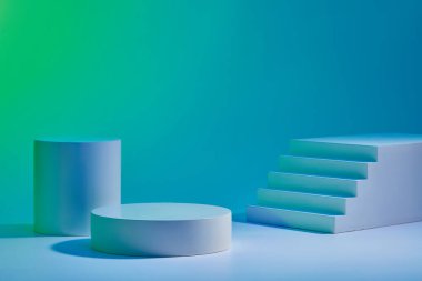 Mavi arka planda iki yuvarlak silindir podyum ve küçük merdiven düzenlenmiş. Ürün markası sunumu için minimalist biçime sahip soyut arkaplan, kopyalama alanı