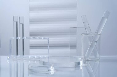 Şeffaf yuvarlak podyum, labaratuar camları renksiz sıvı ve beyaz zemin üzerine süslenmiş akrilik çarşaflarla bilim ve tıbbi arka plan. Ürün sunumu için alan