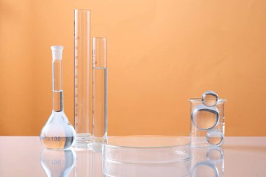 Ters çevrilmiş bir petri kabı ürünleri ve laboratuvar camlarını göstermek için boş bir platform oluşturur. Renkli arka planda cam bir top. Bilim laboratuarı araştırma ve geliştirme kavramı