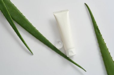 Kozmetik ambalaj tasarımı için markasız plastik tüp modeli beyaz arka planda aloe vera yaprakları ve cam top. Sağlıklı cilt ve saçlar için doğal aloe vera cilt bakım ürünleri.