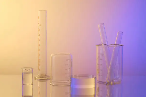 Lab theme with lab glassware - test tubes, beaker and transparent empty podium on gradient background. Blank space for advertising. Science laboratory research and development concept