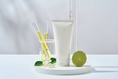 Plastik şişe etiketsiz limon özü reklamı sahnesi, beyaz arka planda limon ve laboratuvar bardakları sarı sıvıyla dolu. Doğal kozmetik ürünlerinin araştırılması ve üretimi