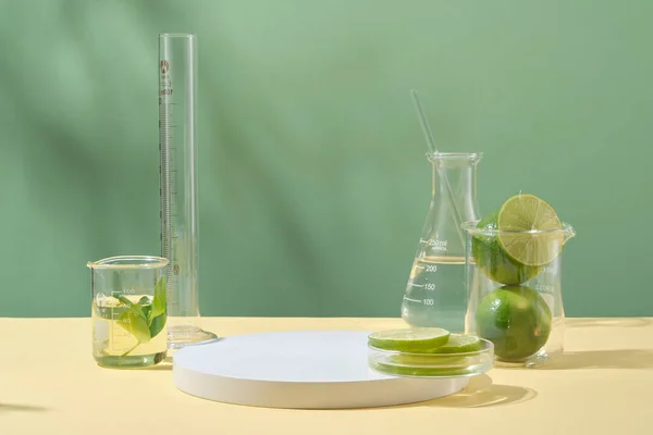 带绿色背景的实验室玻璃器皿的新鲜石灰的正面视图 用于展示石灰提取物化妆品的空空间 概念实验室和研究天然提取物制造化妆品 — 图库照片