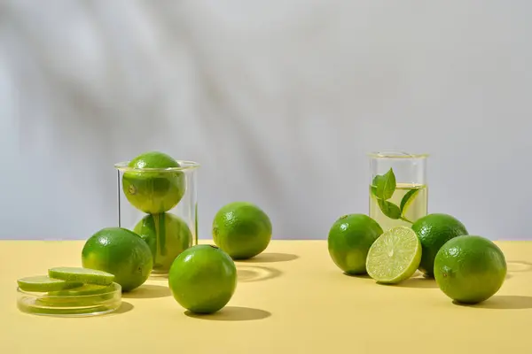 Vooraanzicht Van Verse Limoenen Laboratoriumglaswerk Gedecoreerd Witte Achtergrond Met Schaduwbladeren — Stockfoto