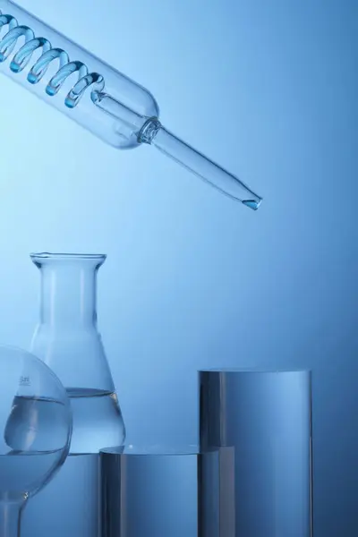 Framifrån Laboratorieutrustning Fylld Transparent Lösning Och Cylinder Podiums Blå Bakgrund — Stockfoto