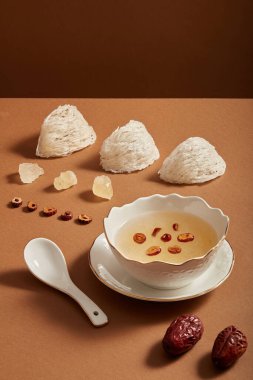 Kase çorba, çiğ kuş yuvası, kaya şekeri ve kahverengi arka planda Jujube. Vietnam, Çin ve Güneydoğu Asya 'da popülerdir. Reklam fotoğrafı, kopyalama alanı.