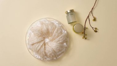 Tepside kuş yuvası, etiketsiz cam su şişesi ve arka planda çiçek dalı. Kırlangıç Yuvası 'nın üretimi için taklit sahnesi - sağlık gıdaları, yaşlanmayı önleme, bağışıklık sistemini güçlendirme