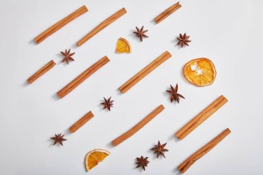 Tarçın çubukları, anason ve kuru portakal dilimleri beyaz arka planda. Doğal bitkisel özün ürünü için reklam fotoğrafı. Üst manzara, düz uzanma.