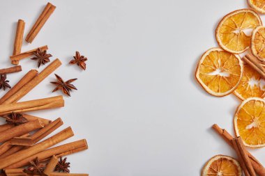 Tarçın çubukları, anason ve açık arkaplanda kurutulmuş portakal dilimleri ile çerçevelenmiş. Doğal bitkisel özün ürünü için reklam fotoğrafı. Metin ve tasarım için alan. Boşluğu kopyala.