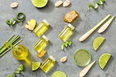 Gerekli yağ şişeleri ve gri arka planda petri kabı. Taze bitkisel - limon kabuğu, limon otu ve zencefil. Sağlık, cilt bakımı ve saç bakımı için iyi. Üst manzara, düz uzanma.