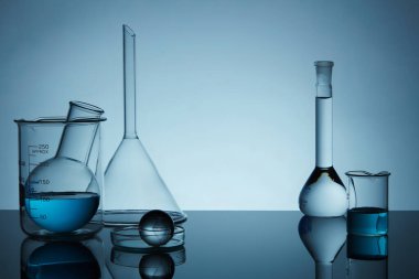 Laboratuvar ekipmanlarıyla dolu boş minimum konsept arka plandaki mavi sıvıyı doldurdu. Laboratuvar teması. Bilim ve tıp geçmişi