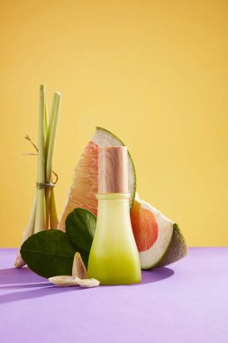 Pembe pembeli ve limonotlu özüt ürünleri için boş şişe sahnesi ve sarı arka planda yeşil yapraklar. Metin ve tasarım için boş alan. Ön görünüm.