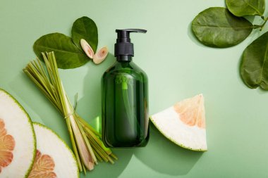 Pomelo ve limon otu özü ve yeşil arka planda yeşil yapraklar için boş şişe maketi sahnesi. Tasarım için alan. Güzellik ürünleri tasarımı, cilt bakımı ve saç bakımı