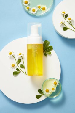 Boş bir şişe ateşinin olduğu, antioksidan özelliği olan bir maket sahnesi. Şişe beyaz podyuma, taze ateş ve mavi arka planda yeşil yapraklar. Tasarım için alan. Üst manzara, düz uzanma.