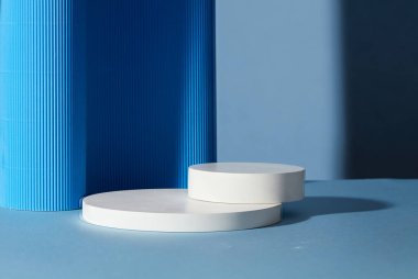 Üst üste dizilmiş, mavi arka planda süslenmiş iki boş yuvarlak beyaz platform. Ürün, metin ve tasarım için boş alan.