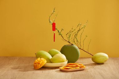 Mango ve mango reçeli Tet tatilinde yaygın meyvelerdir. Sarı arka plandaki ahşap masada ön manzara. Yeni yılda geleneksel meyve. Çin Yeni Yıl Kutlaması.