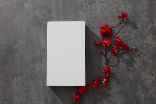 Kırmızı çiçekli beyaz boş podyumun üst görüntüsü göze çarpıyor. Metin veya tasarım için boşluk.