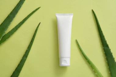 Taze Aloe vera yapraklarıyla beyaz renkli boş bir etiket tüpünün düzlüğü. Aloe vera (Aloe barbadensis miller) deriyi iyileştirebilir ve kırışıklıkları önleyebilir