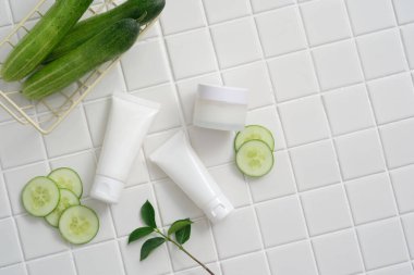 Boş etiketli beyaz tüpler ve yeşil yapraklı salatalık ve salatalık dilimleri ile süslenmiş kavanoz. Salatalıktan elde edilen güzellik ürünleri (salatalık sativus) antiinflamatuar özelliklere sahiptir